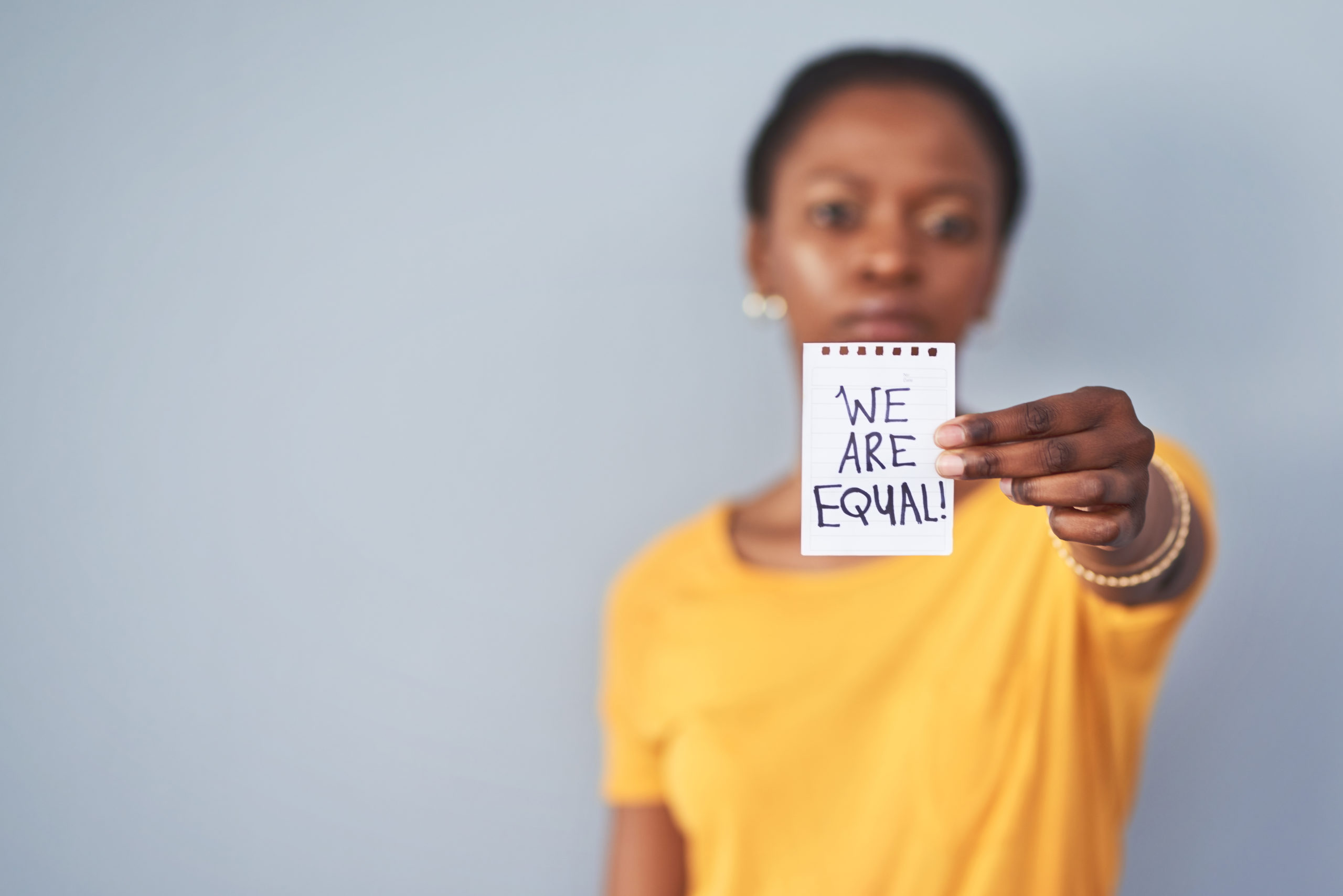 Woman holding up a note that reads "We are equal!"