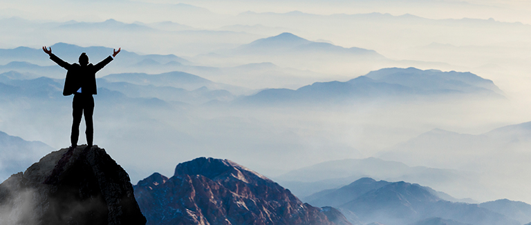 silhouette of businessman standing on top of mountain celebrating